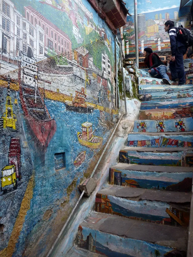 Una scalinata adornata con street art vibrante che raffigura il porto di Valparaíso, unendo arte e storia in un'opera d'arte urbana.