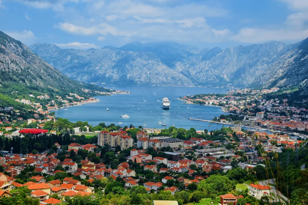 Battello naviga vicino alle imponenti montagne di Kotor.