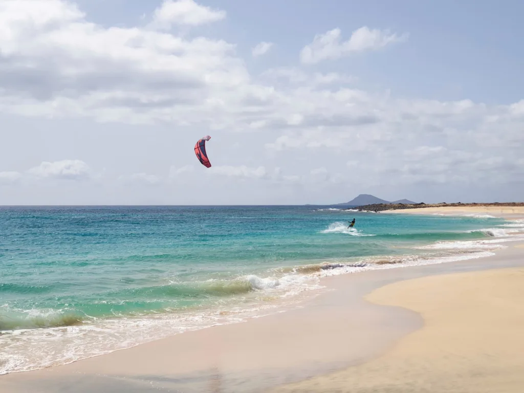 Una fotografia dinamica che cattura l'emozione e l'adrenalina del kite surf nelle acque azzurre di Santa Maria, Capo Verde.